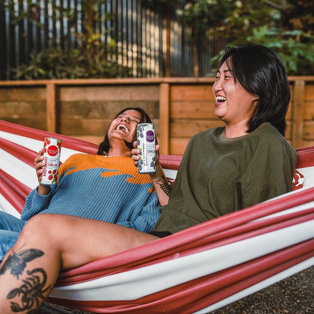 Two friends laughing on a hammock, enjoying Wyld CBD seltzers